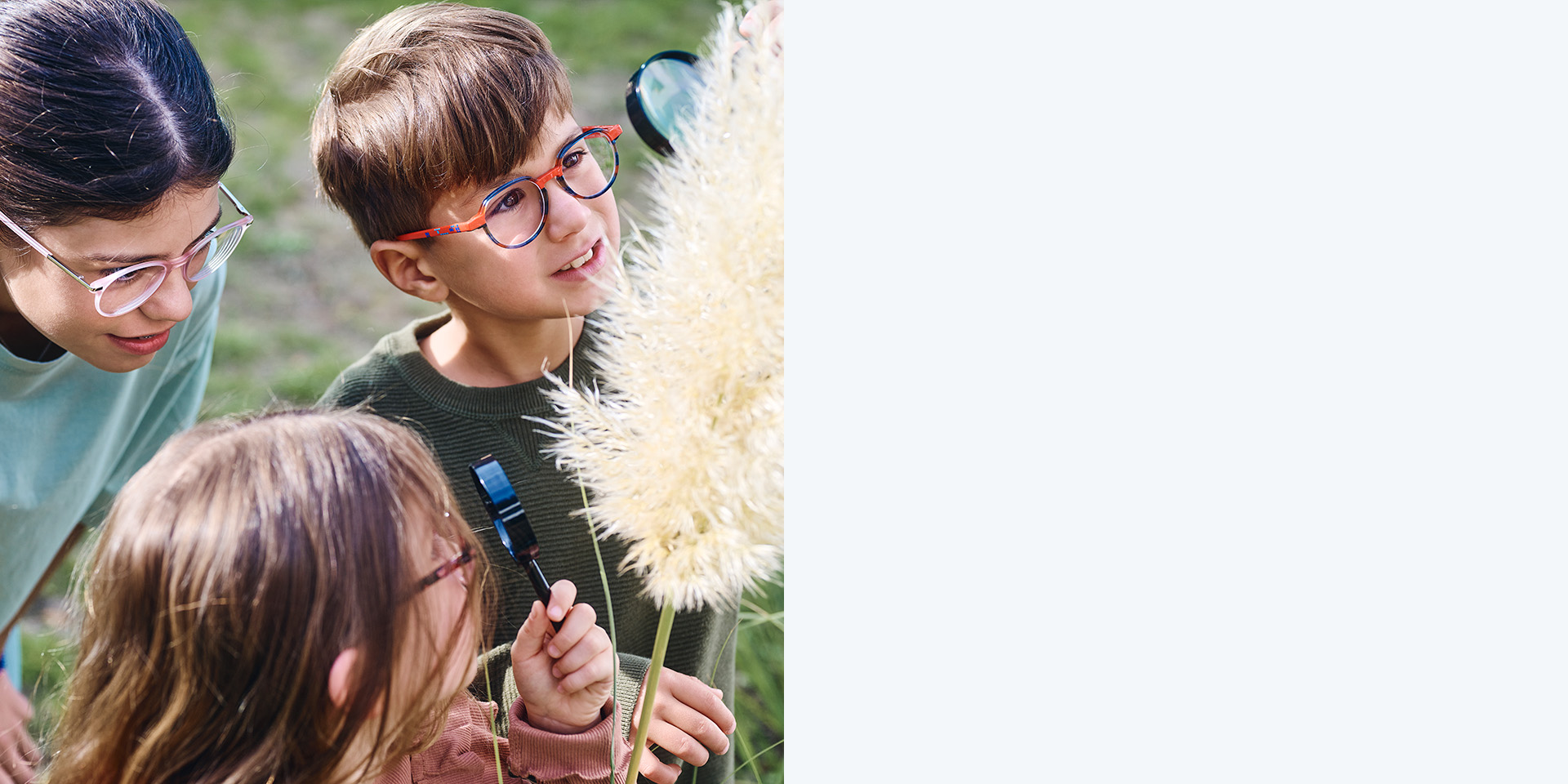 2 girls and 1 boy wearing ZEISS MyoCare lenses. They are looking at a plant, two of the three kids are looking at the plant through magnifying glasses.